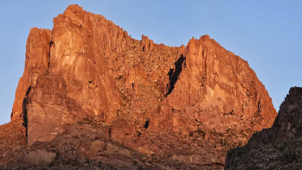 A mountain glowing orange from the sun rising at the start of the Superstition Ridgeline Trail.